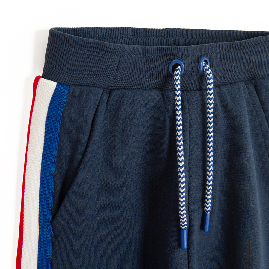 Blue jogging pants with white and red stripes on the side